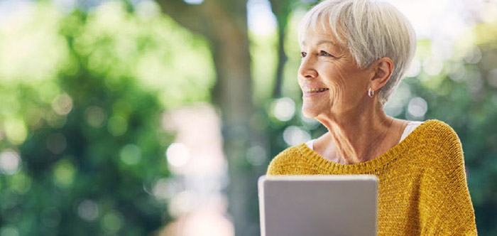 Smiling senior woman outdoors with laptop computer