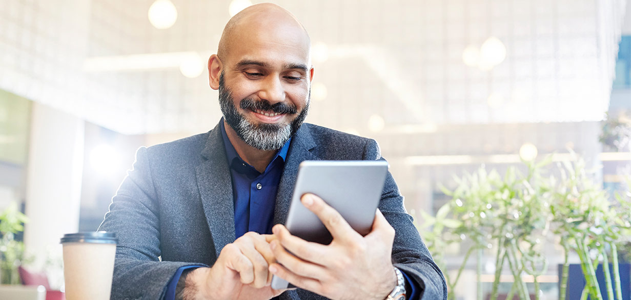 Happy business man in a coffee shop using his smartphone mobile device, Why Travis Credit Union