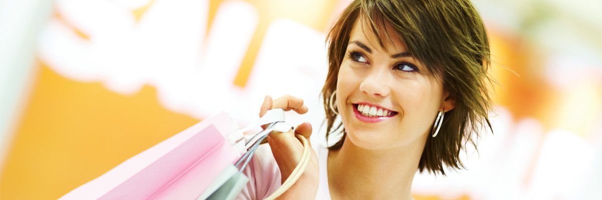 young woman with brunette short hair smiling with shopping bags at a store