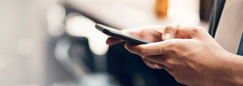 mobile banner close up view of hands holding a smart phone, side view, blurred bokeh background