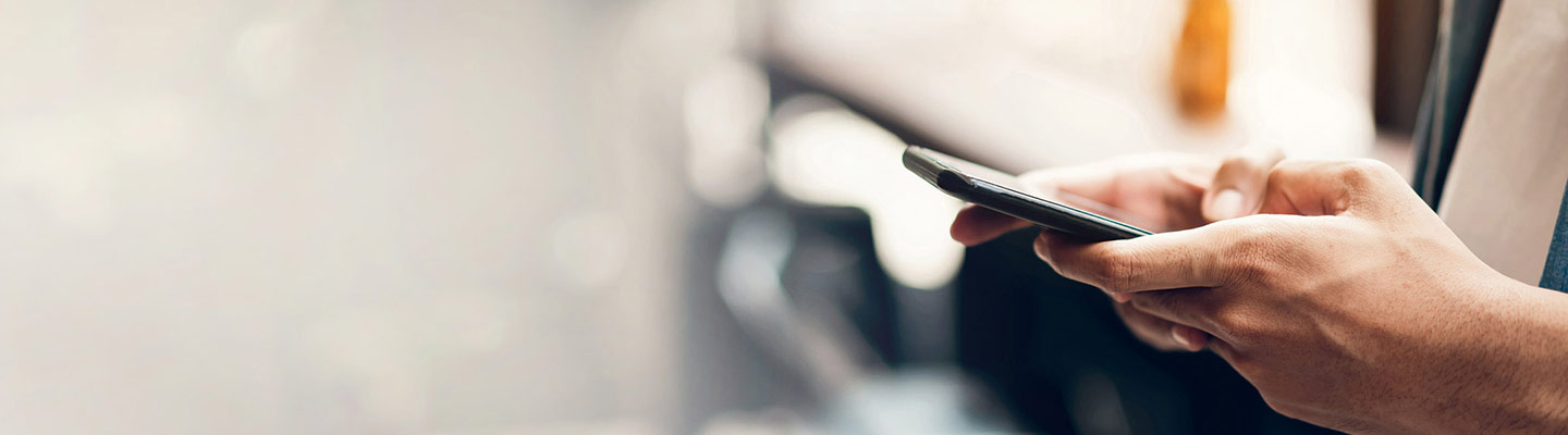 desktop banner close up view of hands holding a smart phone, side view, blurred bokeh background